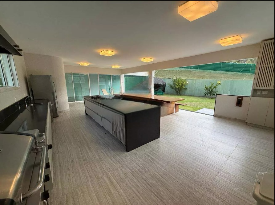 Vista geral da área de lazer com integração entre cozinha, gourmet e jardim