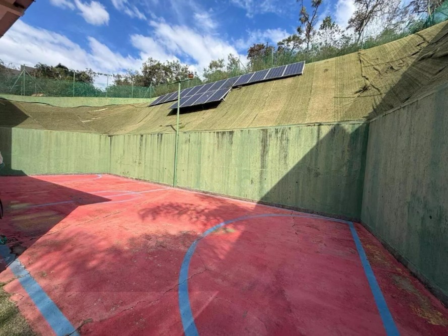 Quadra esportiva privativa com sistema de energia solar ao fundo